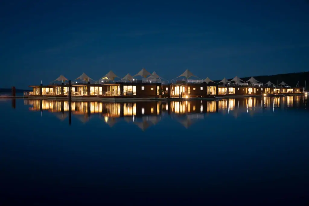 Eco Lodges am Wasser bei Nacht, beleuchtet und reflektiert im See.
