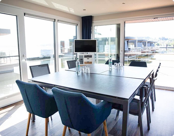 Konferenzraum mit großen Fenstern und Hafenblick, moderne Ausstattung.